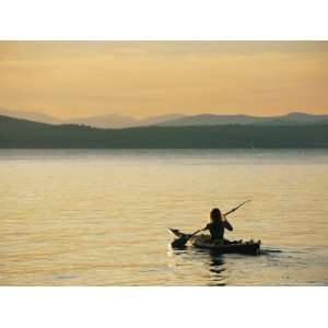 Kayaker Paddles Across Lake Sebagos Calm Waters in Low Sunlight 